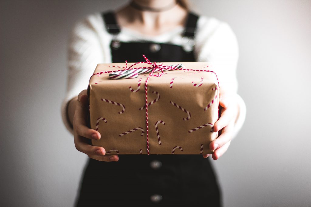 Girl with pinafore holding out Christmas Present